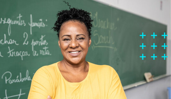 Professora dentro da sala de aula sorrindo.