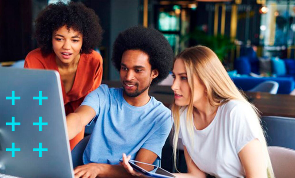 grupo de três estudantes concentrados olham e gesticulam para computador