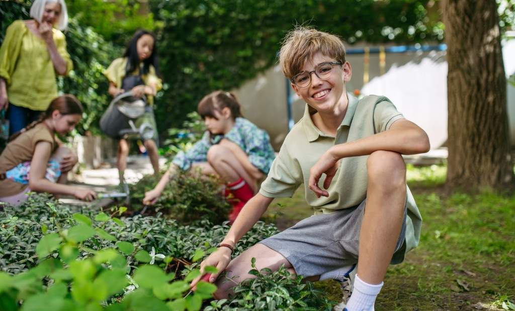 crianças plantando mudas em projeto escolar de sustentabilidade.