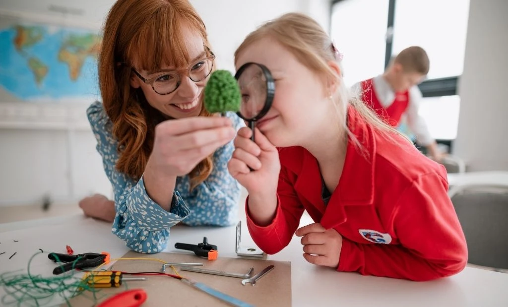 Professor ajudando uma jovem estudante a explorar ciência e tecnologia com uma lupa e objetos de laboratório, representando inovação para crianças.