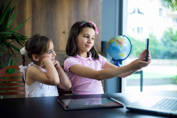 Duas irmãs crianças usando tablet digital e laptop em casa.