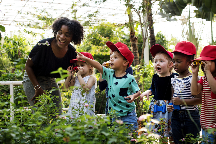 Professor e crianças aprendendo jardinagem ecologia.