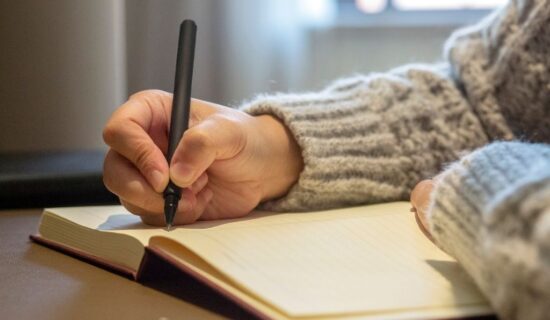 pessoa escrevendo em caderno com caneta preta.